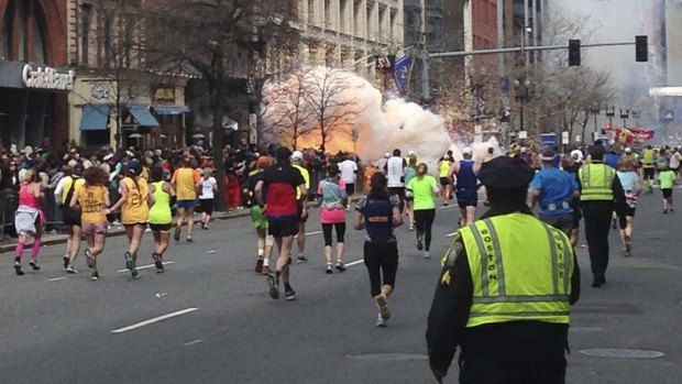 Runners continue towards the finish line of the Boston Marathon as a bomb detonates. 