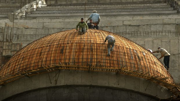 Two workers high above the Arahman Mosque being constructed in Baghdad in 2003.