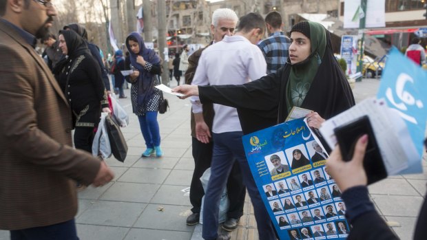 A woman distributes election posters in downtown Tehran.