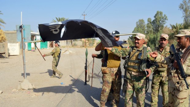 Iraqi soldiers take down an IS flag outside the city of  Ramadi last week.
