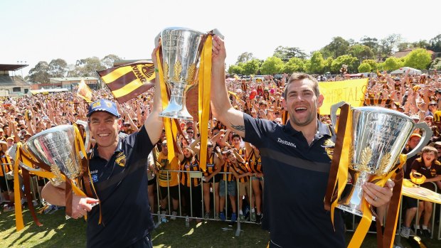 Alastair Clarkson and Luke Hodge show off Hawhtorn's trio of premiership trophies.