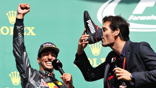 Mark Webber drinks champagne from the boot of Daniel Ricciardo of Australia and Red Bull Racing on the podium during the Formula One Grand Prix of Belgium.