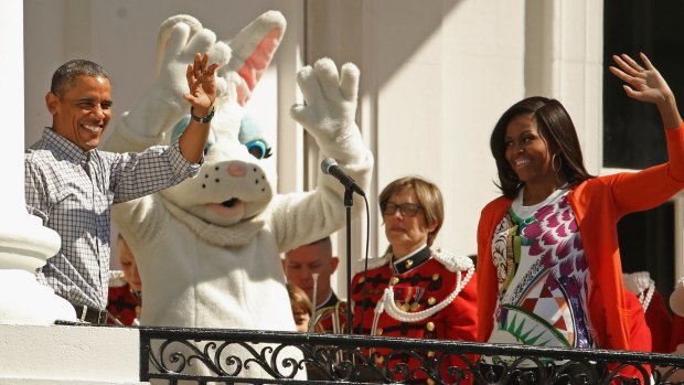 President Barack Obama and first lady Michelle Obama wave to visitors from the Truman Balcony during the White House Easter Egg Roll on the South Lawn of the White House.