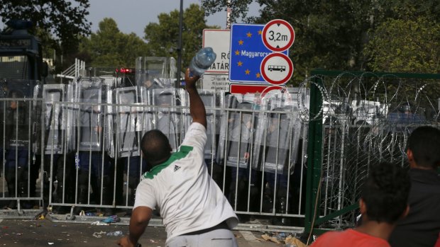 A migrant throws a bottle toward Hungarian police at the 'Horgos 2' border crossing into Hungary.