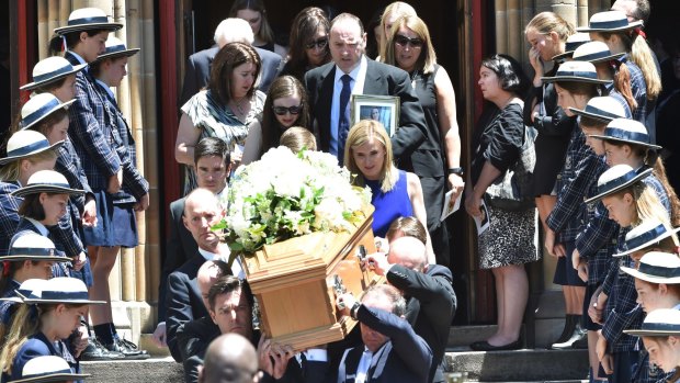 "She did not deserve this": Georgina Bartter's family, her mother in blue, her father holding a photograph, walk behind her casket at St Marys, North Sydney.