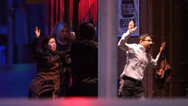 Freed hostages run from the Lindt Chocolat Cafe in Martin Place.