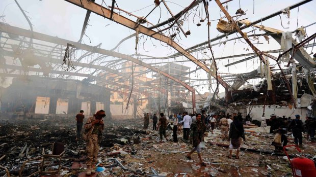 People inspect the aftermath of October strike on the Sanaa reception hall, which killed at least 100 people and injured hundreds more.
