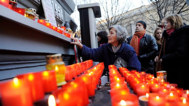 People light candles on the wall of the House of Terror Museum in Budapest.