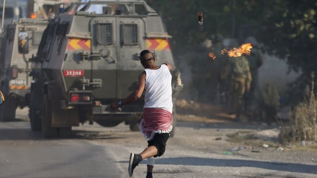 A Palestinian protester throws a petrol bomb towards Israeli soldiers at the Jalazoun refugee camp after the death of Laith al-Khalidi in Friday protests there.