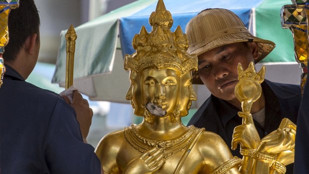 Workers clean a statue of Hindu god Brahma at the Erawan Shrine, the site of the deadly blast.