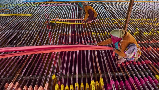 Hanging textiles to dry on bamboo rods in a sari factory.