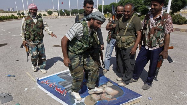 A Free Syrian Army fighter from the Al-Faruk brigade steps on a portrait of Syrian President Bashar Assad in 2012.