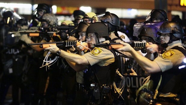 Police officers point their weapons at demonstrators in Ferguson in August.