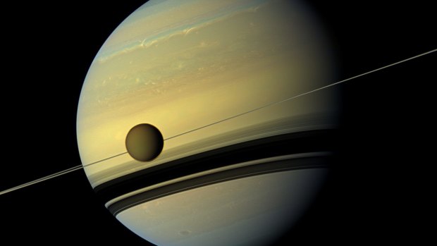 A giant of a moon appears before a giant of a planet undergoing seasonal changes in this natural colour view of Titan and Saturn from NASA's Cassini spacecraft. 