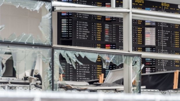 An arrivals and departure board and blown-out windows at Zaventem Airport in Brussels. The airport has reopened using a temporary check-in terminal.