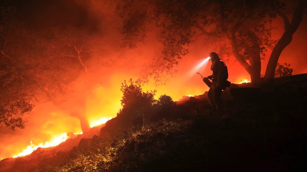 A San Diego Cal Fire firefighter monitors a flare ahead of a wildfire above the Sonoma Valley.