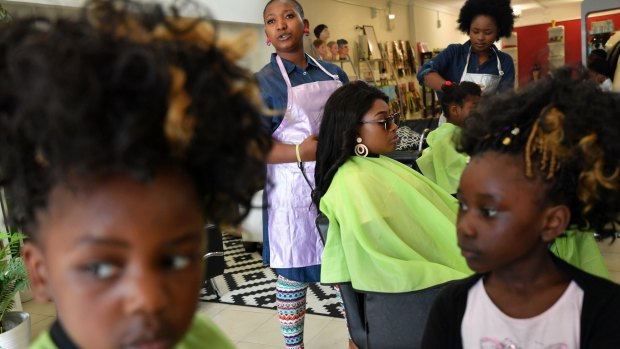 Olivia Mpia, 4, and sister Naomi, 6, at Lisese Hair Salon in Werribee with owner Chimene Mumbanga and customer Jolie Mpia (in chair) and assistant Magalie Masudi.