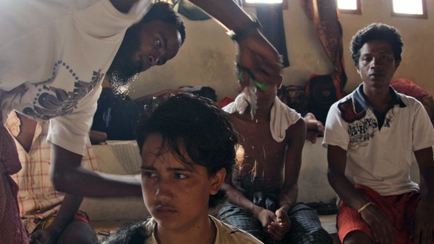 A migrant helps cut his friend's hair at a sports stadium that was turned into a temporary shelter in Lhoksukon, Aceh province, Indonesia on Tuesday.