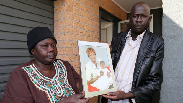 The children's father Joseph Tito Manyang and their grandmother Umjuma Deng hold a photo of Akon Guode and her daughter Awel.