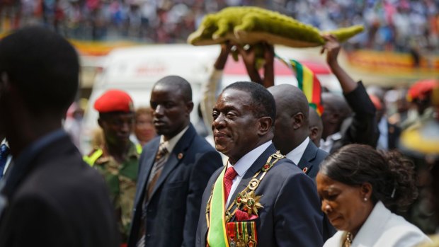 Mnangagwa, center, known as "The Crocodile" for his ruthlesness, and his wife Auxillia, right, leave the stadium as a supporter holds a stuffed crocodile behind.