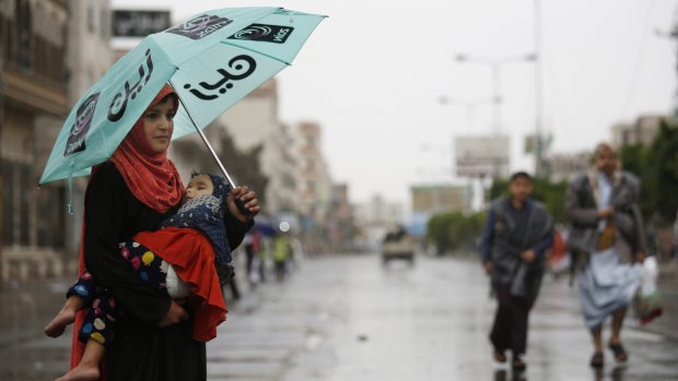 A girl carrying her sister stands in a Sanaa street begging for money following a protest against Saudi-led airstrikes by Shiite rebels, known as Houthis.