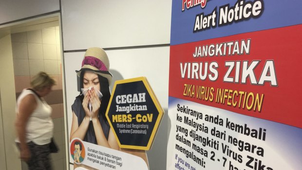 A traveller walks past a travel advisory on the Zika virus infection in Kuala Lumpur International Airport.