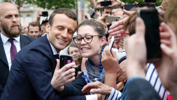 Emmanuel Macron, left poses for a selfie after a ceremony at the Arc de Triomphe.