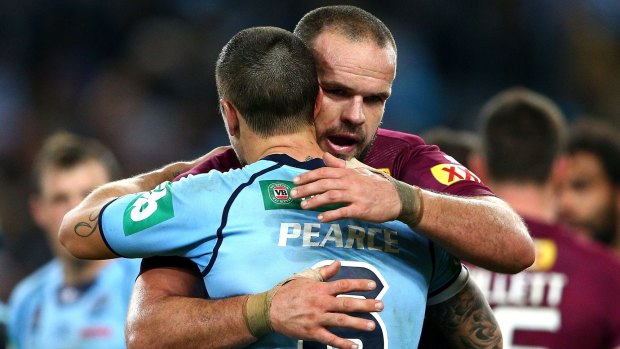 Fierce battle: Former club team mates Nate Myles and Mitchell Pearce embrace.