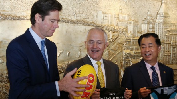 Prime Minister Malcolm Turnbull watches AFL chief Gillon McLachlan catch a Sherrin during a signing ceremony with Guojie Gui from Shanghai CHEN real estate in Shanghai on April 14.
