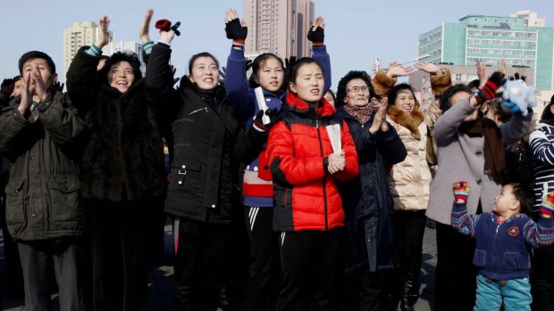 North Koreans react as they watch a news broadcast on a video screen outside Pyongyang Railway Station.