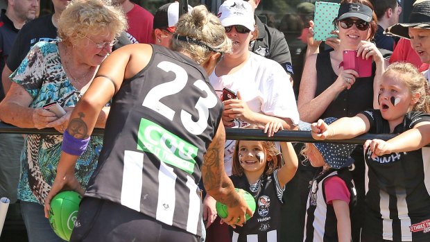 Moana Hope gives a footy to a young Collingwood fan.