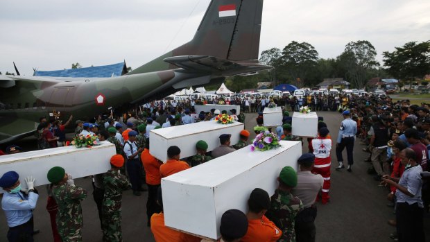 Bodies recovered from the sea are carried to a military transport plane to be taken to Surabaya.