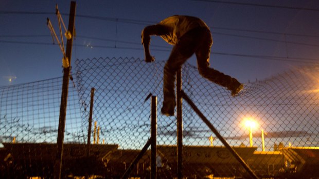 A migrant jumps a fence to get the Channel Tunnel in Calais.