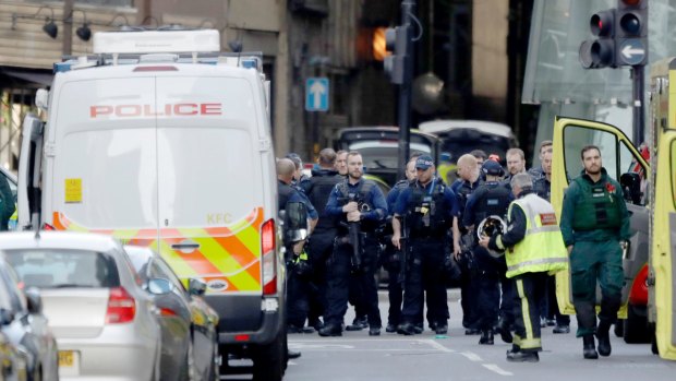 Armed British police officers walk within a cordoned off area after the attack. 