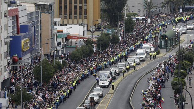 Thousands line the streets as Pope Francis waves to the crowd in Quito on Sunday. 