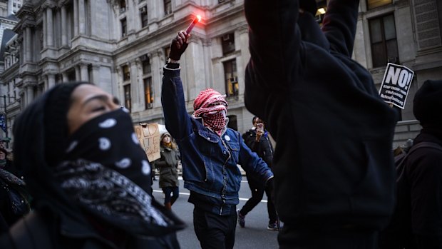 A demonstrator holds up a flare during a protest outside the US Republican Party's annual policy retreat in Philadelphia on Thursday.