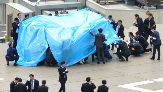 Police covered the drone with blue tarpaulin on the rooftop.