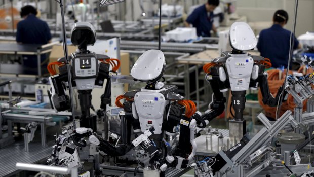 Humanoid robots work alongside employees at a Glory Ltd factory in Japan.