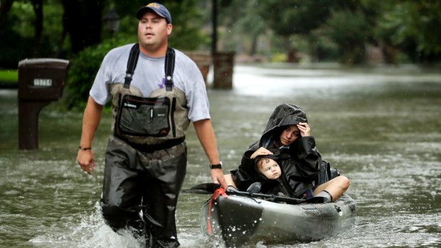 People evacuate a neighborhood inundated by floodwaters from Tropical Storm Harvey on Monday.