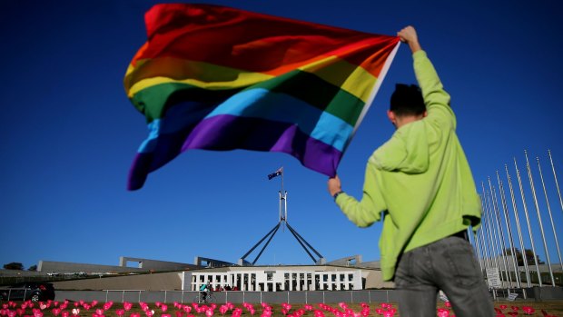 Marriage equality advocate Russell Nankervis poses with the rainbow flag during a 'Sea of Hearts' event in support of marriage equality on the front lawn of Parliament House.