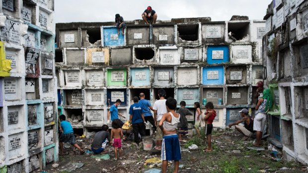 Shanty dwellers living inside the cemetery look at bodies being buried in Manila, Philippines.