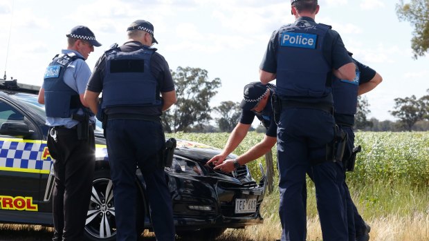 Police examine damage to a police car that may have been involved in accident during the Stocco manhunt west of Wangaratta.