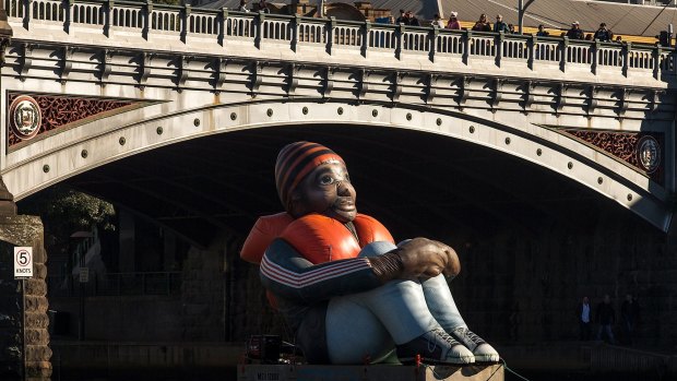 Inflatable Refugee floats along the Yarra River before it is temporarily installed at Melbourne's Immigration Museum.  