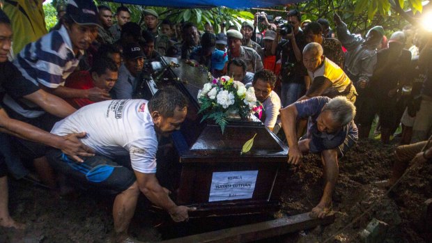 The coffin of Hayati Lutfiah Hamid is lowered in a funeral in the suburb of Desa Sawotratap.