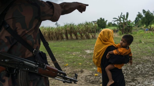 A Bangladeshi border guard sends a Rohingya woman and child back to their makeshift camp along the border with Myanmar last month.