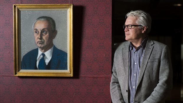 Curator Nat Williams with a portrait of Sir Rex Nan Kivell in a show of Kivell's collection at the National Library of Australia.
