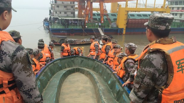 Rescue workers carry a boat as they conduct a search, after the ship sank in the Jianli section of the Yangtze River.