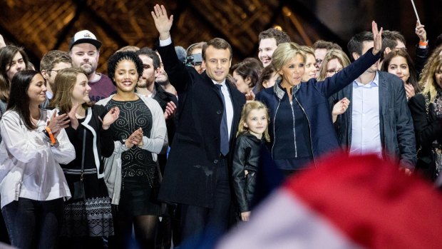 Emmanuel and Brigitte Macron at his victory party at the Louvre in May, with one of her grandchildren standing between them.