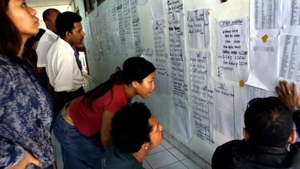 Balinese scan lists of names lining the walls of the Sanglah hospital in Denpasar on October 14, 2002.