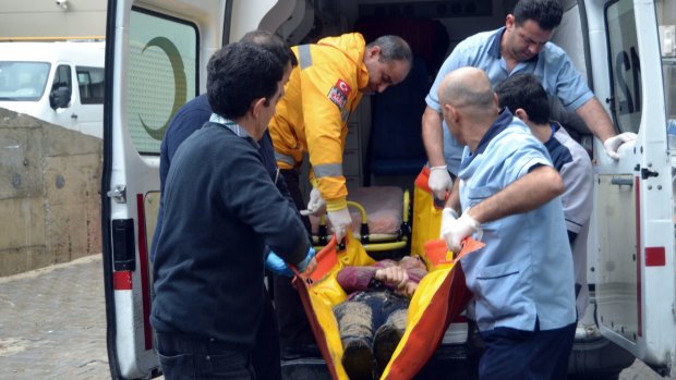 A Turkish rescue worker and medics carry the body of a migrant to an ambulance in Ayvalik.